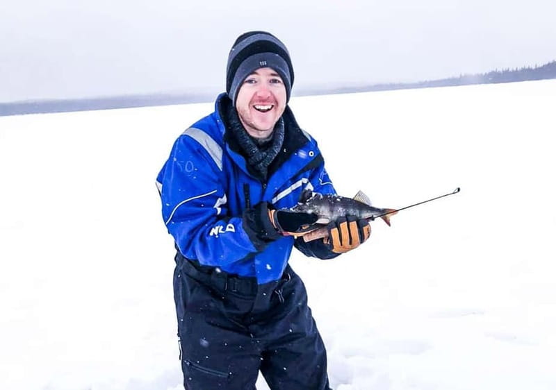 Snowshoe Trip for Ice Fishing in Saariselka - Drilling through the ice on a frozen lake